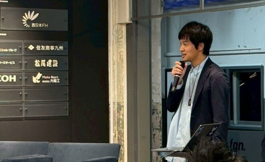 会場でマイクを持って登壇し、話している様子