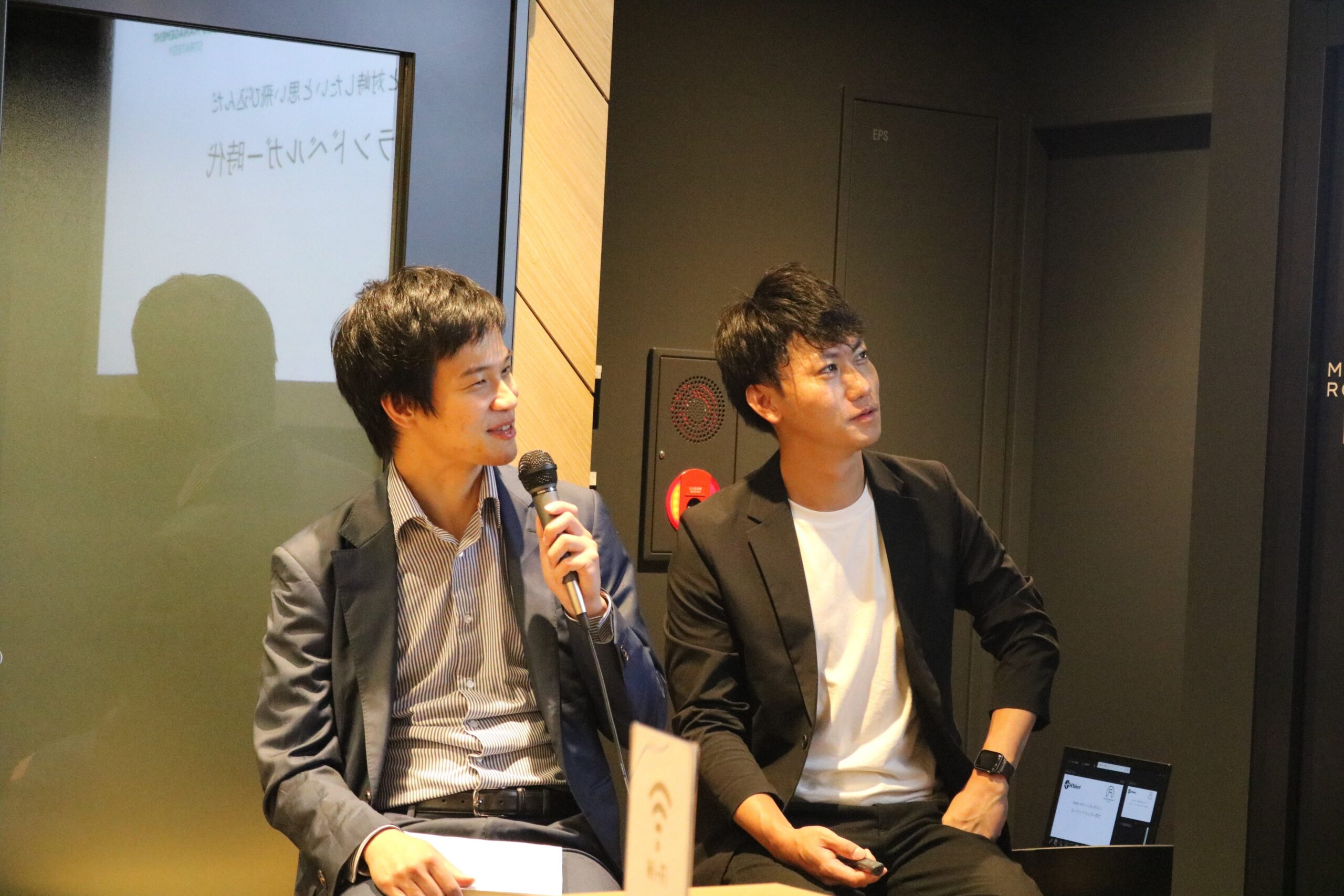 セミナー会場で、マイクを持ち対談形式で進む様子