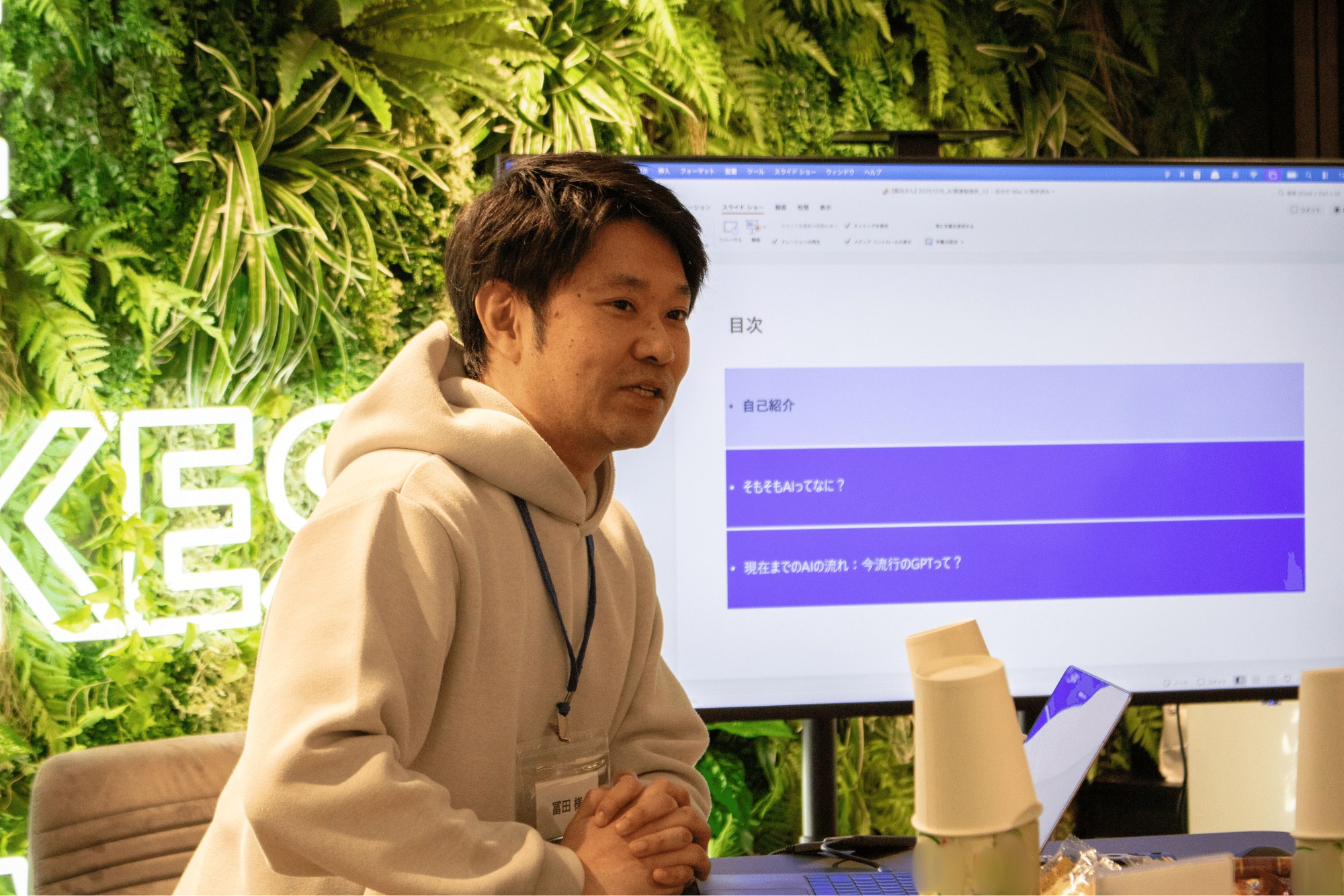冨田氏がライトニングトークを行っている様子。背景のスクリーンには「そもそもAIってなに?」「現在までのAIの流れ」が並ぶ目次スライドが映っている