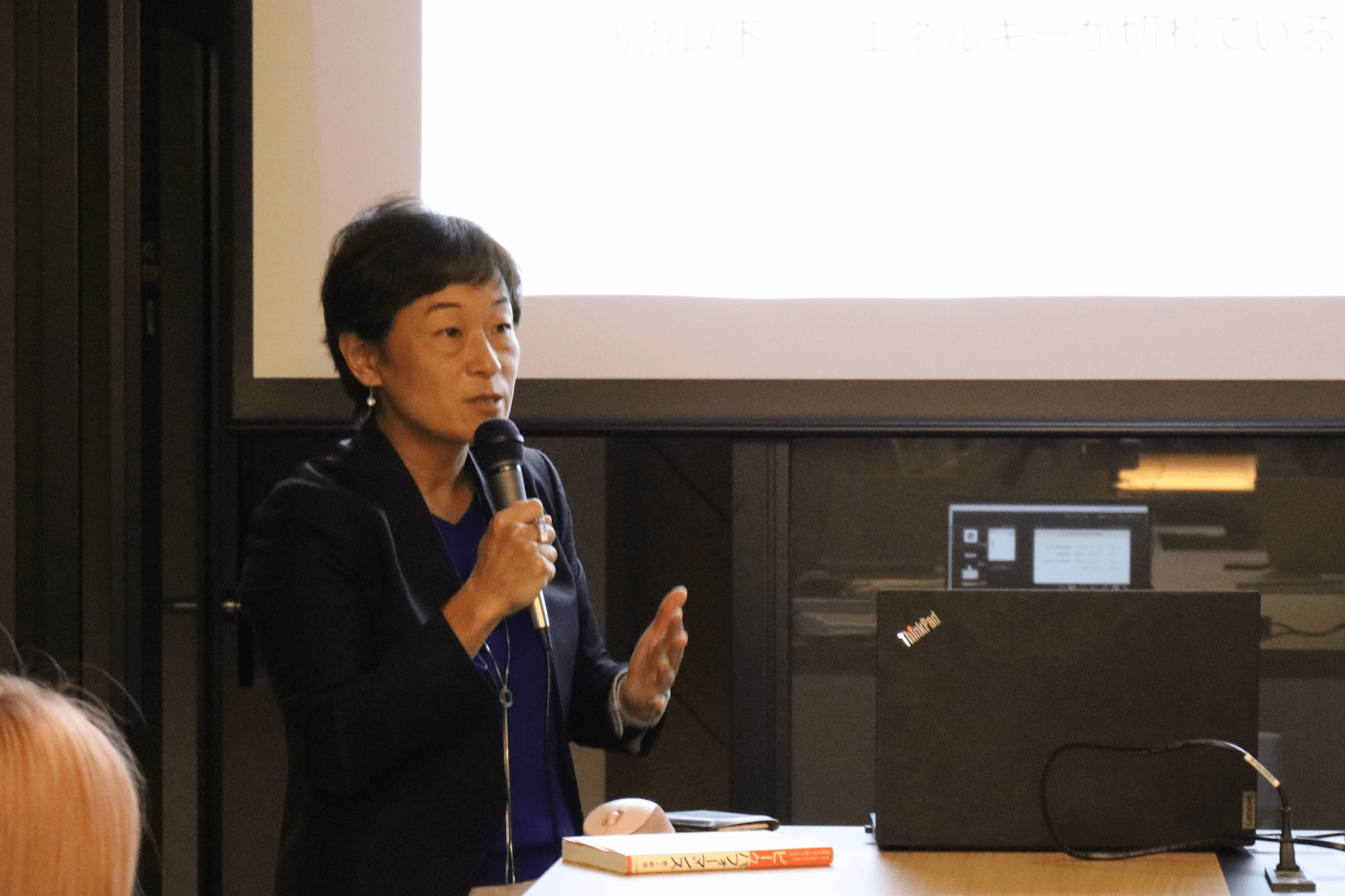 スクリーンを背に、マイクを持って講演する野上麻理氏